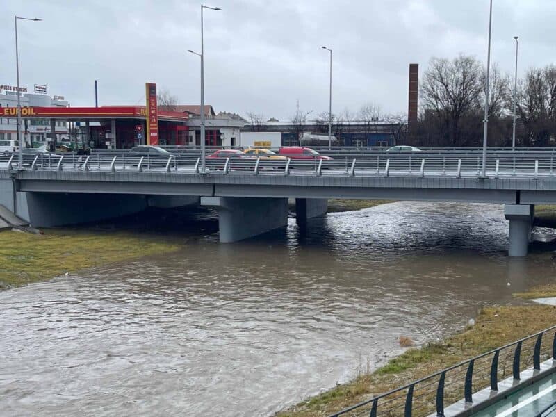 râul cibin cu debit crescut și apă tulbure, curgând pe sub un pod rutier din sibiu